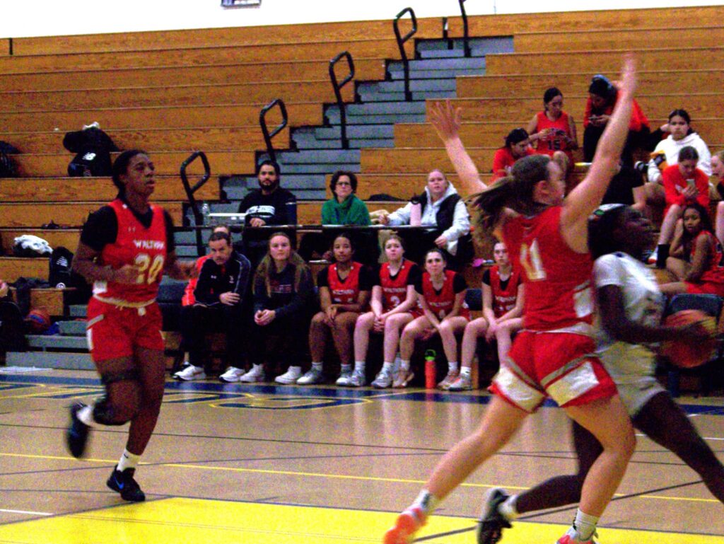 An AB player runs down the court past a couple of Waltham girls.