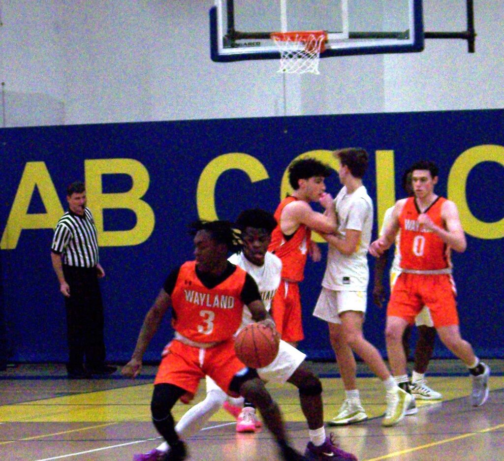 A player in an AB jersey sneaks up behind a Wayland player who currently has the ball (but possibly not for long).