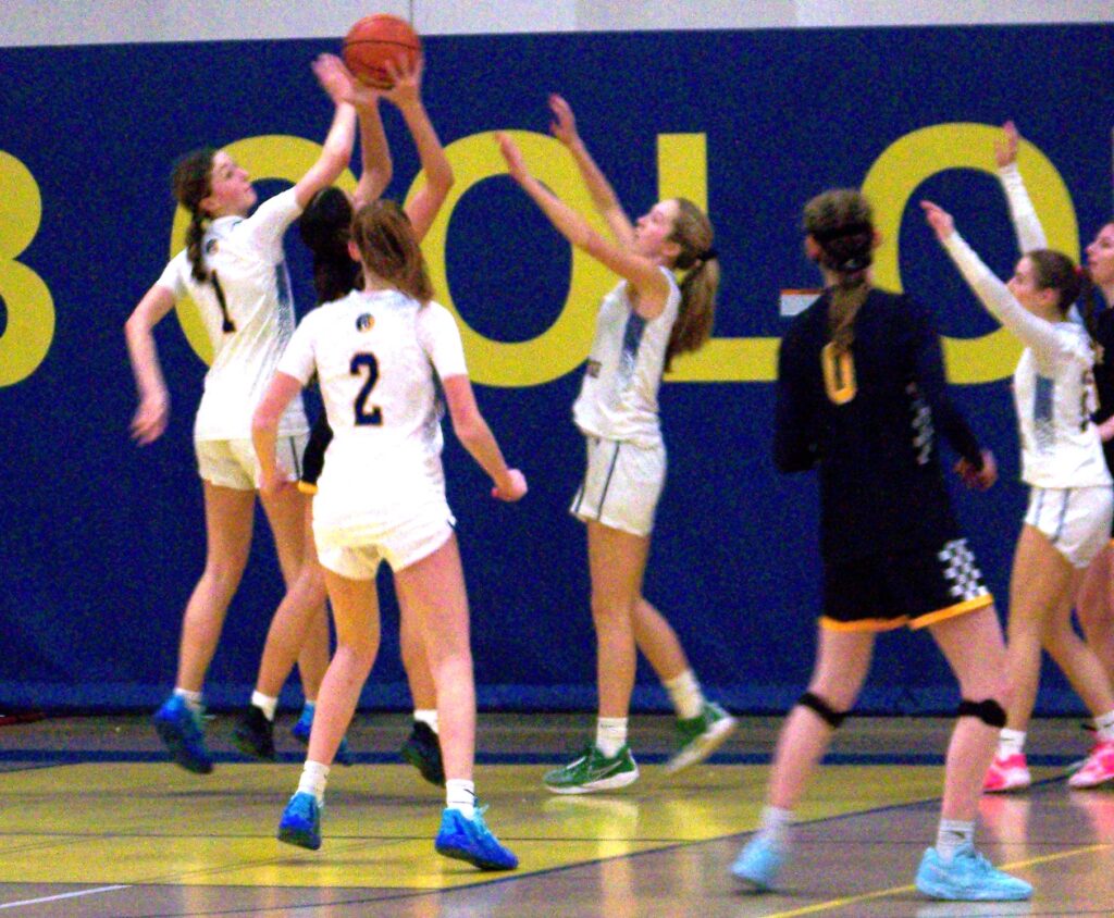 Three players in AB jerseys surround another player who is holding the basketball high.