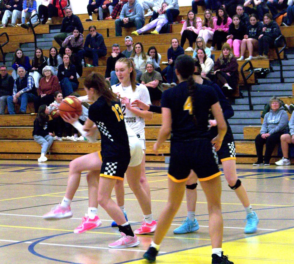 A pair of legs and arms wearing AB colors grabs the ball from behind a black clad player.