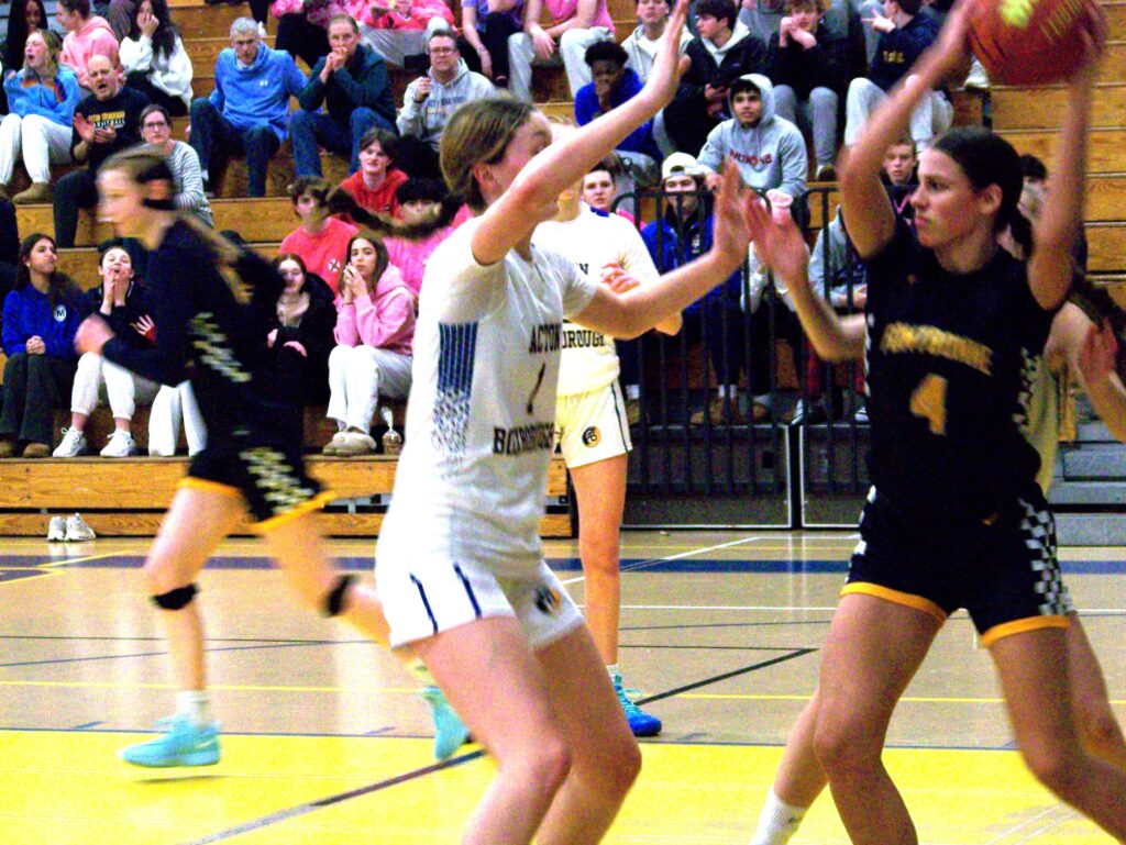 Three players in AB jerseys surround another player who is holding the basketball high.