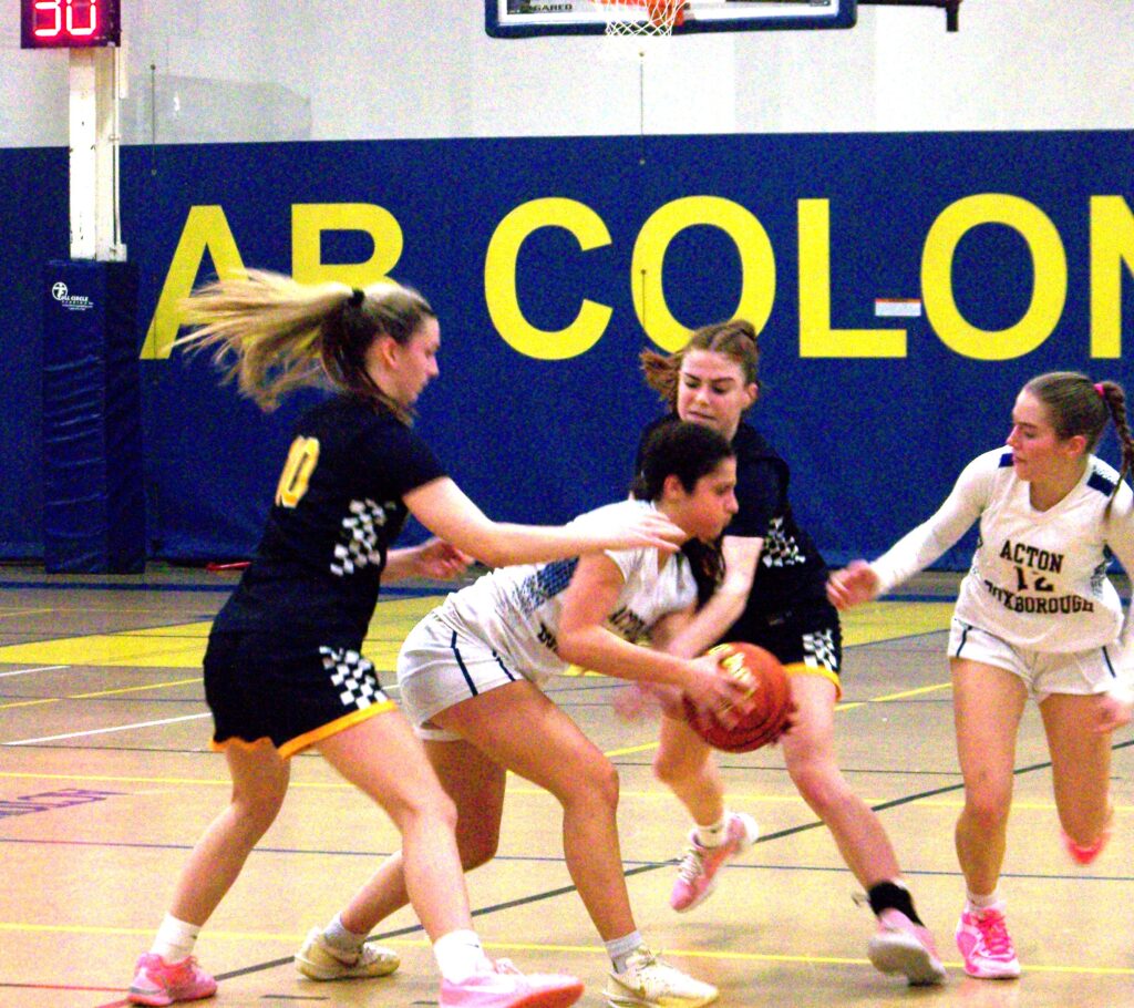 A girl in a white (AB) jersey holds the basketball while two players in black jerseys surround her. Another AB player is running up to help.