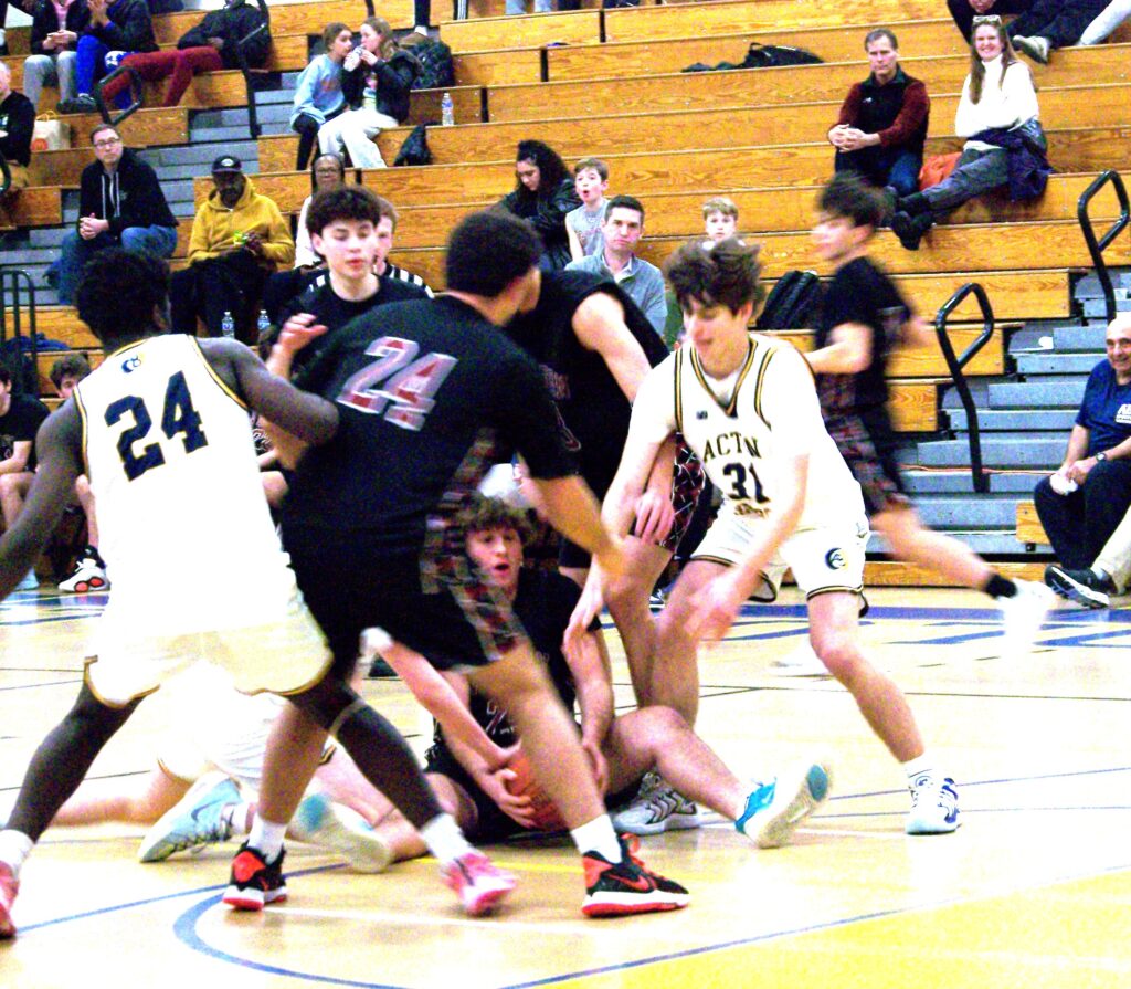 A group of players are in a scrimmage. A Weston player has the ball, but he's sitting on the ground.