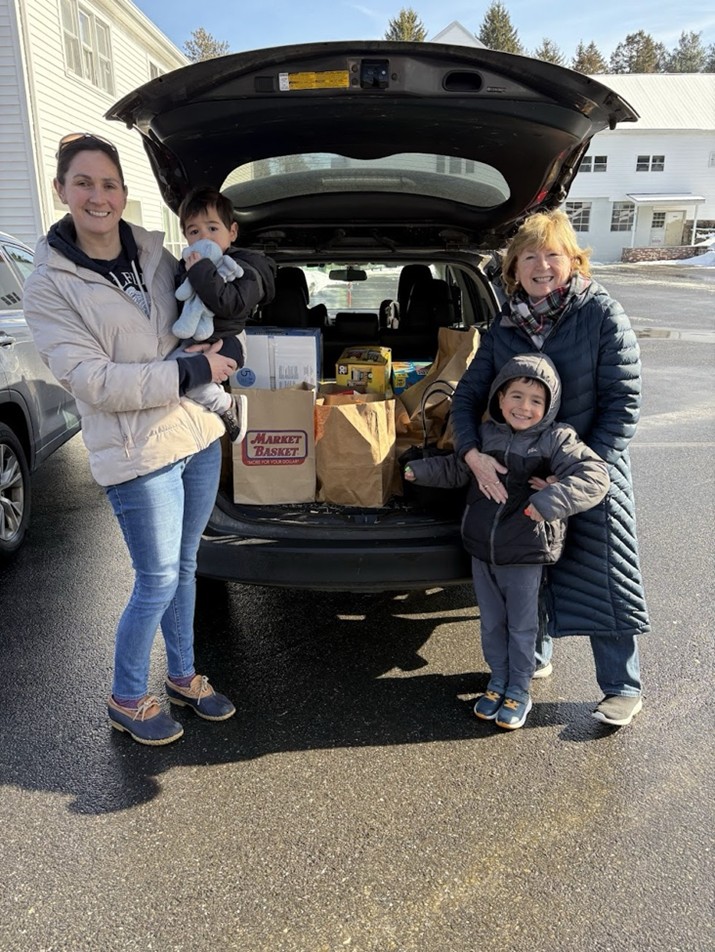 Four people in front of a minivan. The trunk is open and full of grocery bags. There's a young mom with a small child on one side of the car, and her mother with a slightly older child on the other.