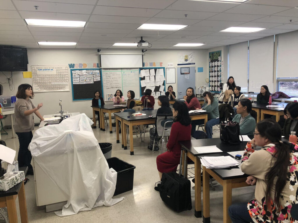 A classroom of adults listening to a teacher.