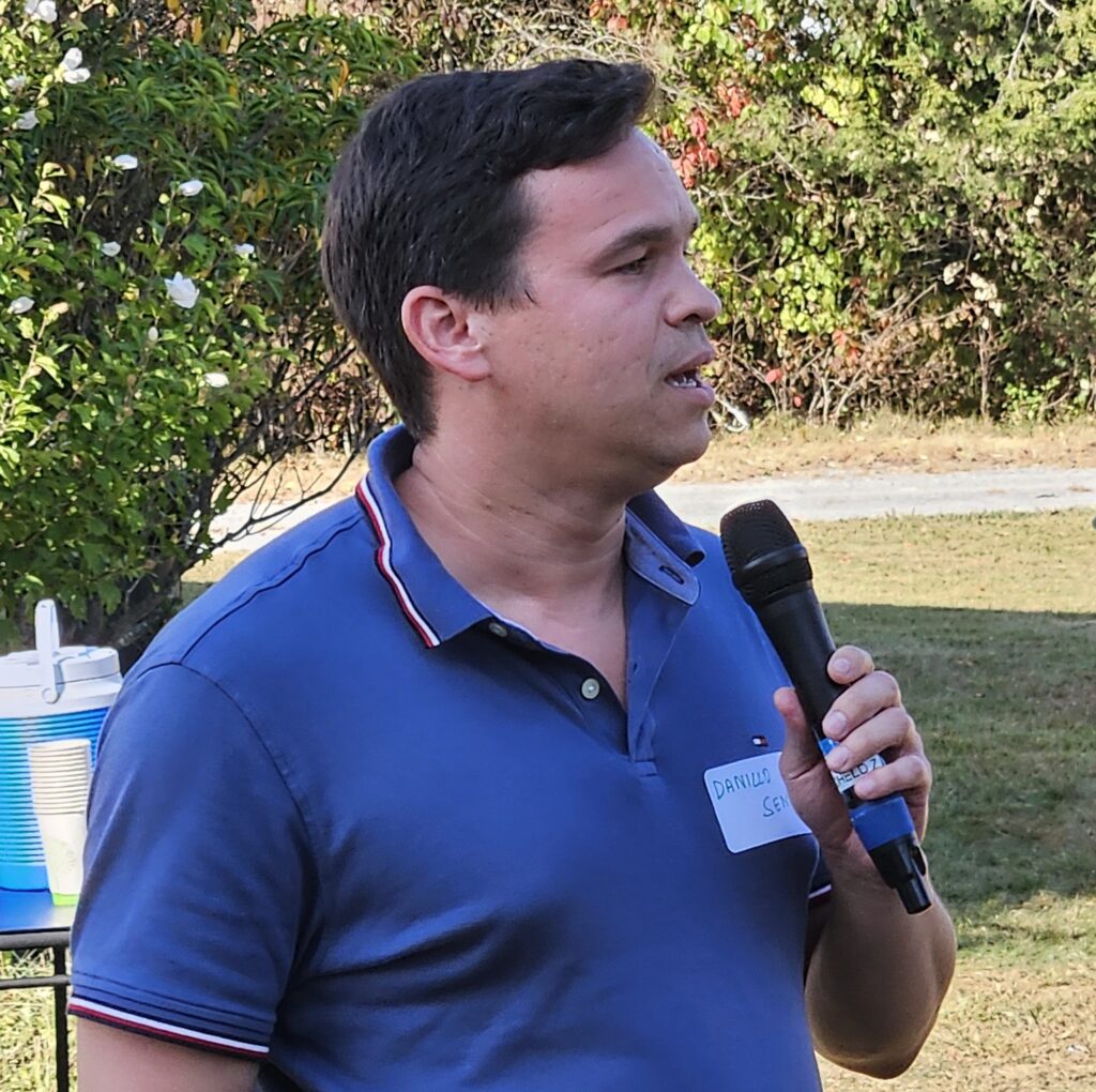 A man in a golf shirt speaks into a mic.