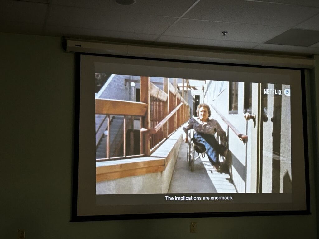 A man in a wheelchiar heads down a wooden ramp.