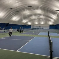 People playing pickleball under a very large bubble.