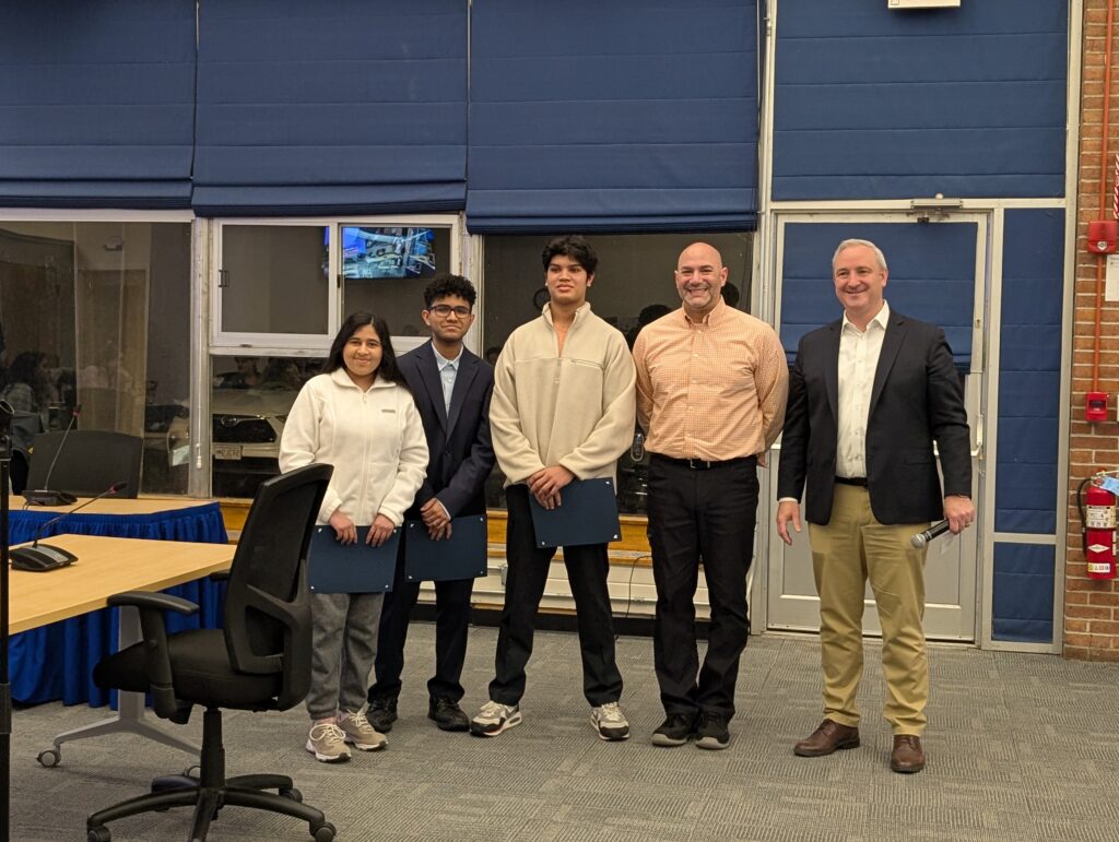 Three students and two adults pose proudly.